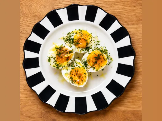 Soft-boiled eggs with herbs on a black-and-white striped plate