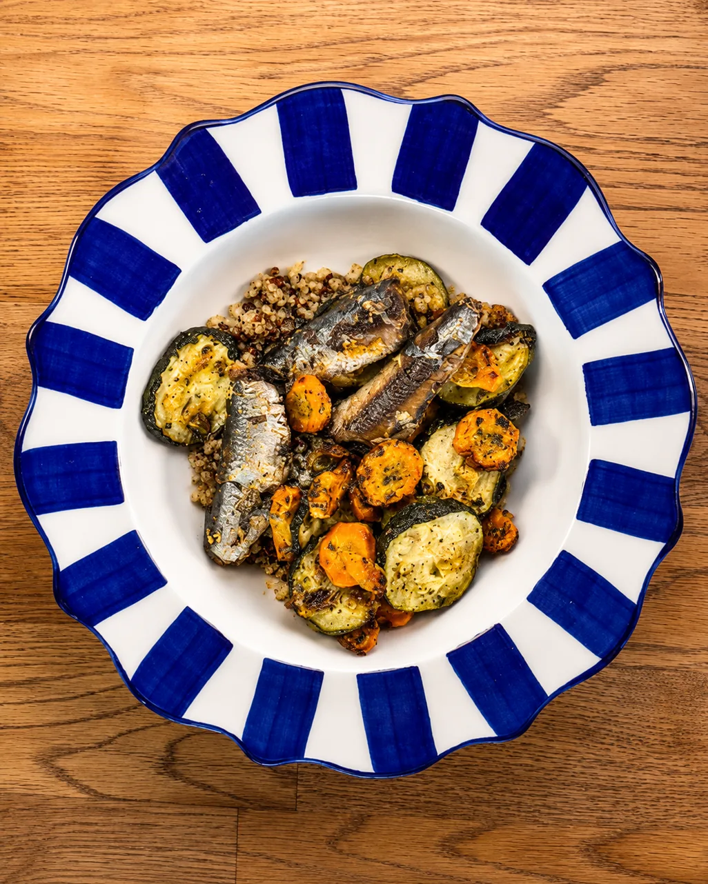 Baked sardines with roasted carrot and zucchini on a blue-and-white striped plate